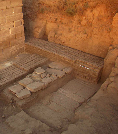 Partie nord-ouest de la chapelle d'Osiris Ounnefer Neb-Djefaou avec, au premier plan, le dallage d'un édifice antérieur à la construction de l'enceinte (© C. Giorgi)